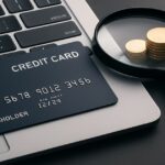 ノートパソコンの上に置かれたクレジットカードと拡大鏡のコインが並ぶ、クレジットカード比較サイト向けのアイキャッチ画像