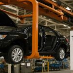 自動車工場で搬送ラインに吊り下げられ移動する黒いセダン車の組立工程